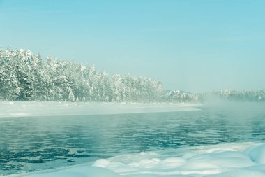 Kış nehrinin üzerinde kar ve orman kıyılarında dondurucu bir sis var. Soğuk bir günde göldeki ilk buz.