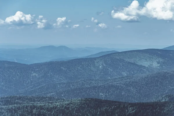 Dağların üzerinde kalın bulutlar, mavi sisli tepeler.