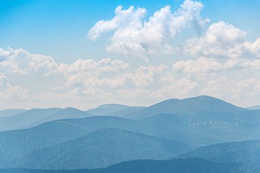 Dağların üzerinde kalın bulutlar, mavi sisli tepeler.