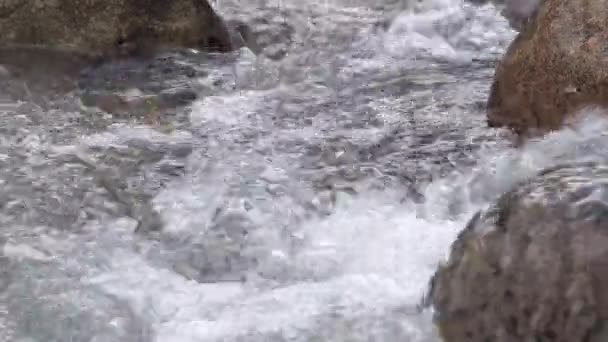 Water seethes between three boulders. — Stock Video