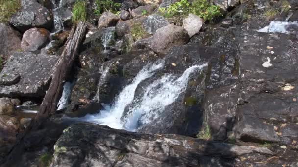 La cascada tormentosa fluye sobre rocas. El agua fluye y cae sobre piedras — Vídeo de stock
