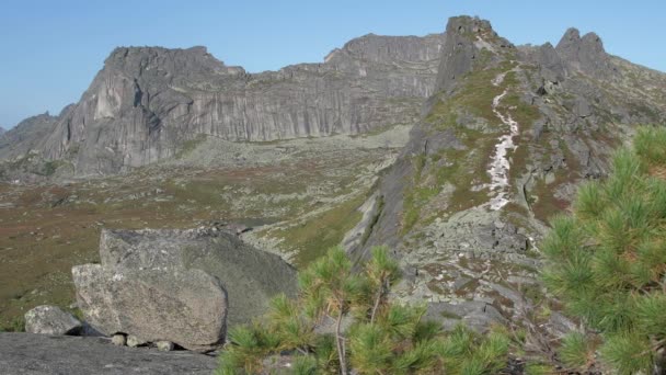 Cerro rocoso con pendientes pronunciadas en el horizonte bajo el cielo azul. — Vídeos de Stock