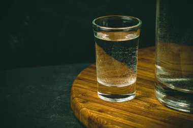 Ahşap masadaki su kabı. Temiz şişenin yanında bir bardak votka. Restoranda alkollü içecekler