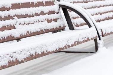 Kış parkındaki ahşap bank karla kaplı. Soğuk şaklatma ve kar yağışı