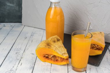 Tahta masada bir bardak taze sıkılmış kabak suyu. Kırsal kahvaltı, sağlıklı fitness yemeği. Bir şişe meyve suyu ve çiftlik ürünü olarak balkabağı.