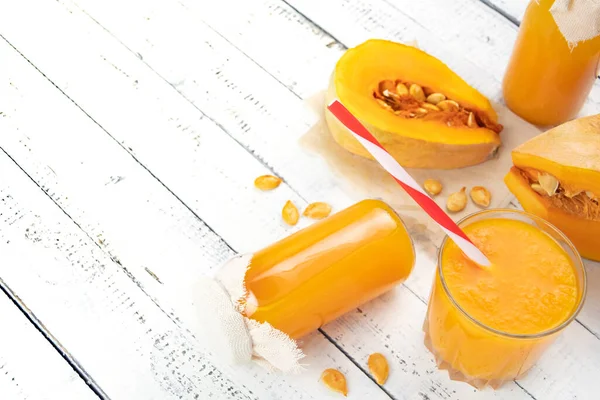 Tahta masada taze sıkılmış balkabağı suyu. Bir parça kabak ve tohum. Bardak ve bir şişe portakal suyu. Sağlıklı yiyecek ve içecekler.