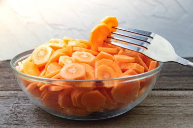 Cam kasede taze havuç dilimleri. Metal çatallı sebze parçası yemek için. Çiftlik ürünleriyle vejetaryen yemekleri pişirmek