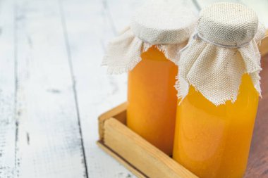 Bottles of orange fresh juice with pulp on wooden. Lids are covered with fabric, rustic style. Fortified drink. Copy space for text