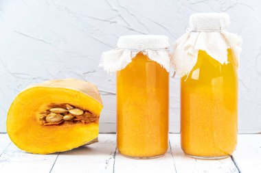 Freshly squeezed pumpkin juice. Piece with seeds and pulp on table. Decoration for halloween. Healthy fortified food. Vegan vegetable smoothie