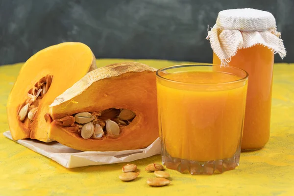 Freshly squeezed pumpkin juice. Piece with seeds and pulp on table. Decoration for halloween. Healthy fortified food. Vegan vegetable smoothie