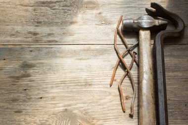 Old rusty nails and hammer, nail puller on wooden background, space for text
