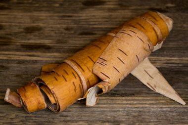 Ahşap bir arka plan üzerinde rulo birch'ın kabuğu yerleştirilmiştir