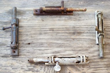 Old metal latch for the door on wooden table. Copy space to right.