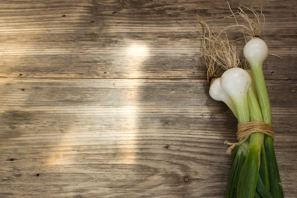 Bunch of fresh green onions on wooden table. Copy space to right. — Stockfoto