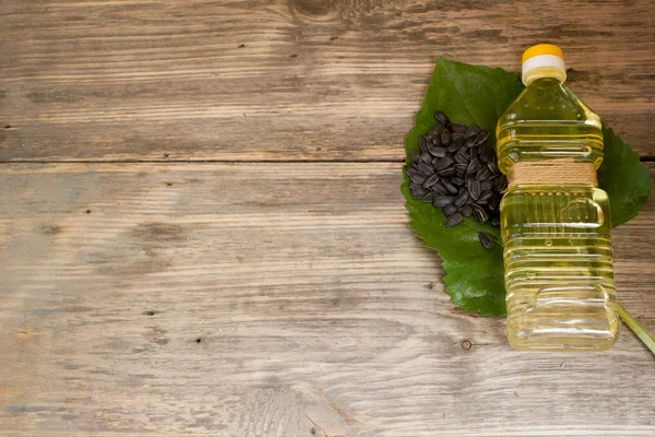 Bottle of sunflower oil and sunflower seeds on wooden background. Copy space to right. — 图库照片