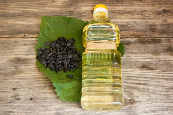 瓶向日葵油和向日葵种子木制背景上 — 图库照片
