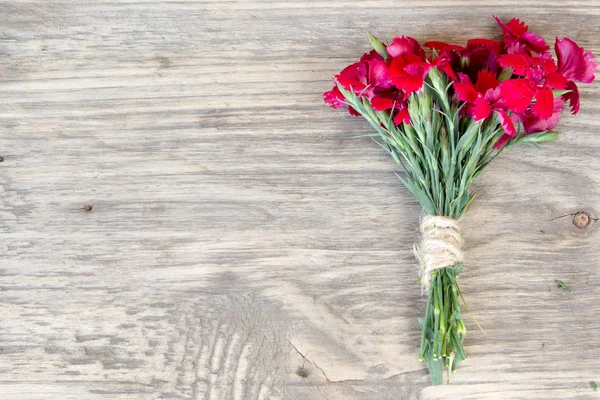 Red carnation over wooden table with copy space — Stock Photo, Image