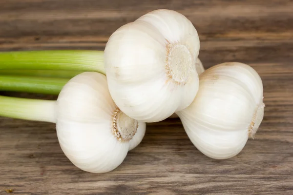 Bulbi di aglio fresco con gambo lungo sul tavolo di legno — Foto Stock