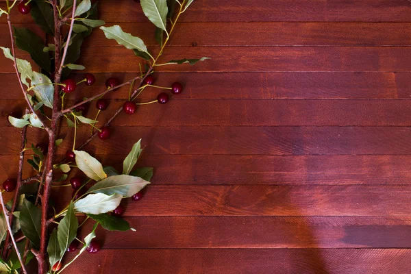 Ripe cherries, leaves on wooden table — Stock Photo, Image