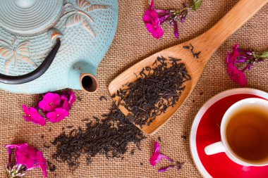 Ateş çiçekler ile kuru siyah çay, çuval bezi arka plan üzerine bir fincan