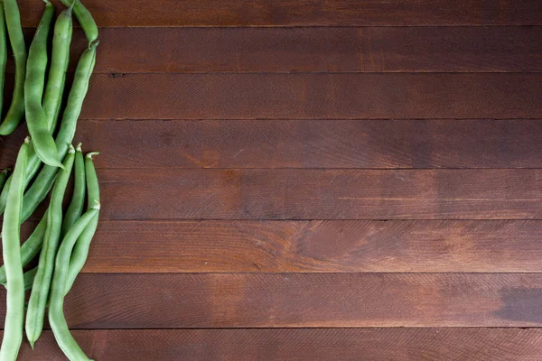 Свежие спелые зеленые бобы кучи на деревянном фоне — стоковое фото