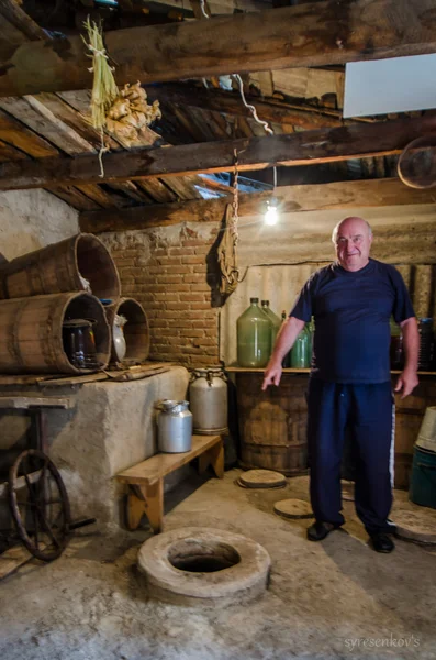 Un homme géorgien âgé montre kvevri dans une vieille maison géorgienne — Photo