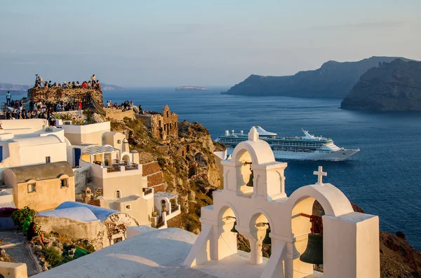 insanlar bir kaya üzerinde oturmak ve denizin üzerinde gün batımını izlemek