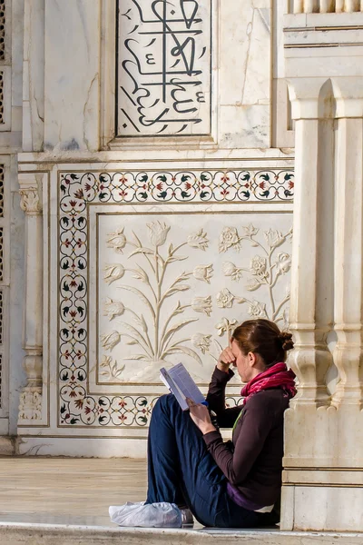 Kız Taj Mahal merdivenlerinde oturmuş ve bir kitap okuma