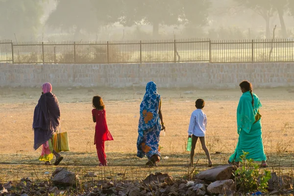 Parti insanlar sabahın erken saatlerinde bir patika üzerinde sabah tuvalete su kabı alanıyla karşıya geç