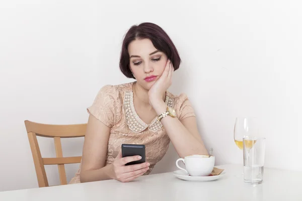 Woman looks disappointed to her mobile phone — Stock Photo, Image