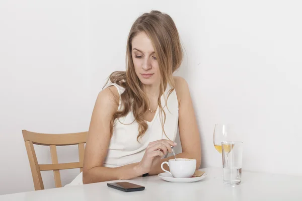 Rubia agitando su café mirando el teléfono móvil —  Fotos de Stock