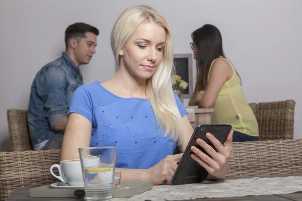 Blonde with tablet sitting in cafeteria — Stock Photo, Image