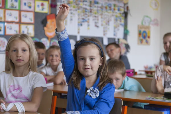 Lagere school meisje verhoogt haar hand — Stockfoto