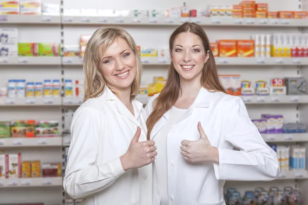 Farmacêuticos segurar os polegares para cima na farmácia — Fotografia de Stock