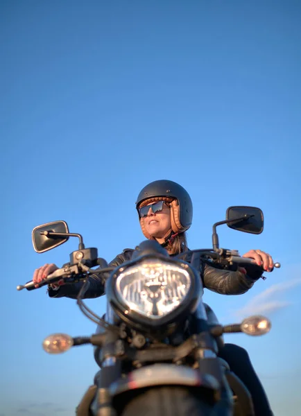 woman on motorcycle with helmet and sunglasses on a blue sky day