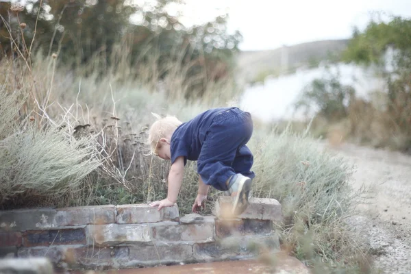 Child climbs up on border — Stock Photo, Image