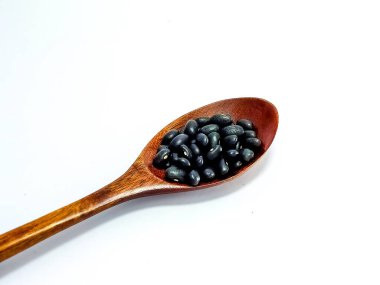 Tahta kaşıklardaki siyah fasulyeler beyaz arka planda izole edilir.. 
