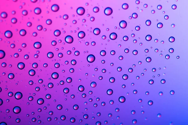 Renkli arka planda bir damla su. Mor ton