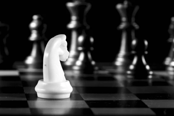 Белый Рыцарь Окруженный Черными Шахматами Шахматной Доске — стоковое фото