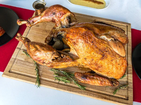 Noel yemeği masası konsepti ahşap kesim tahtasında kızarmış hindi, patates püresi, jambon sosu beyaz masa örtüsü ve kırmızı masa koşucusu.