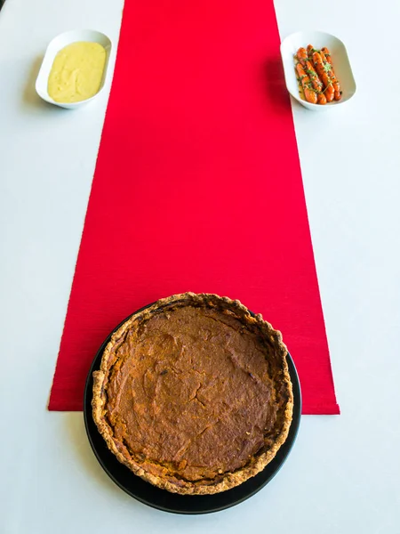 Balkabağı turtası, patates püresi ve beyaz masa örtüsü üzerine jöleli havuç ve kırmızı masa koşucusu.