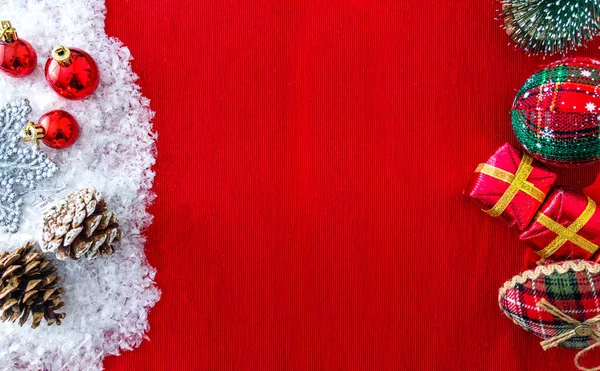 Noel süsleri, kar taneleri ve çam kozalakları, mini çam ağacı, hediye kutuları ve kırmızı bir yüzey üzerinde fotokopi alanı, üst manzara
