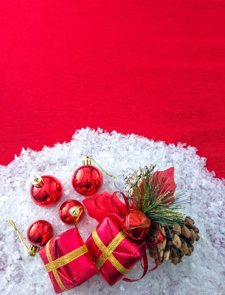 Noel süsleri ve çam kozalakları Noel 'in önünde kırmızı bir yüzey üzerinde karla kaplı kutular, fotokopi alanı, üst görünüm