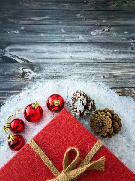 Noel süsleri ve çam kozalakları Noel hediyesi bir kutunun önünde Tahta bir yüzey üzerinde karla fotokopi alanı, üst manzara