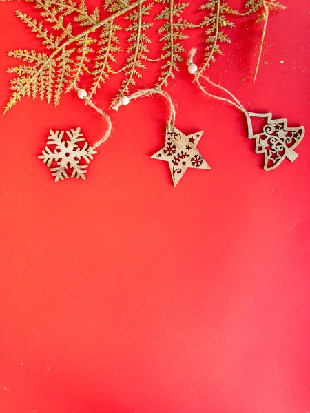 Kırmızı izole bir yüzey üzerinde bir dalla ahşap Noel süsleri, üst görünüm