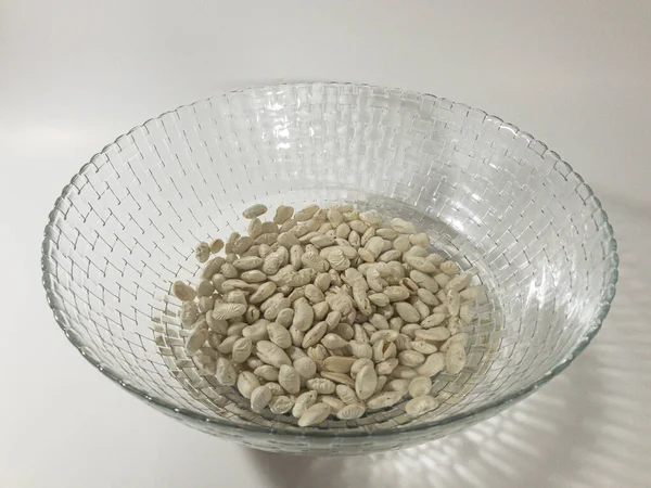 Beyaz arka planda bir kasede sırılsıklam fasulye.