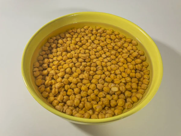 Beyaz arka planda bir kasede ıslanmış nohutlar.