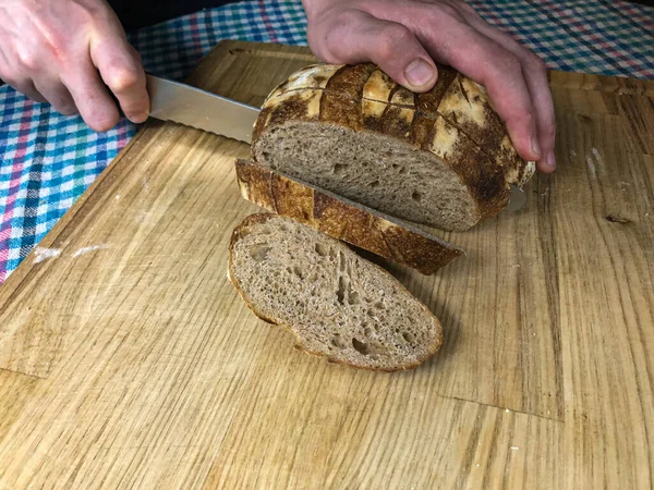 Tahta kesme tahtasının üzerinde buğday ekmeği dilimliyorum.