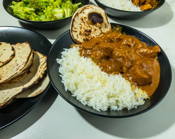 Basmati pilavlı tereyağlı tavuk ve arkasında brokoli olan naan.