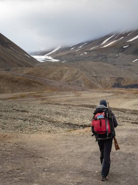 Uzun Yıl Buzulu 'na giden tüfekli adam. Longyearbyen yakınlarında, dünyanın en kuzeyindeki yerleşim yeri. Svalbard, Norveç